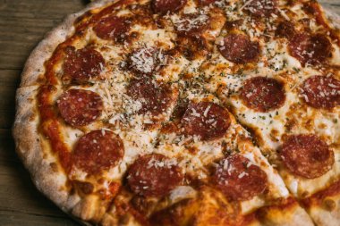 Prosciutto ve ahşap masada salamlı leziz sıcak et pizzası..