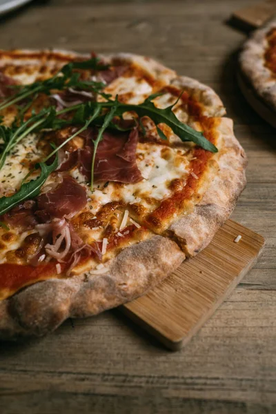 Delicious hot meat pizza with prosciutto and salami on a wooden table. — Stock Photo, Image