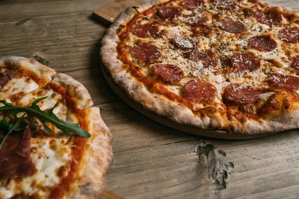 Delicious hot meat pizza with prosciutto and salami on a wooden table. — Stock Photo, Image