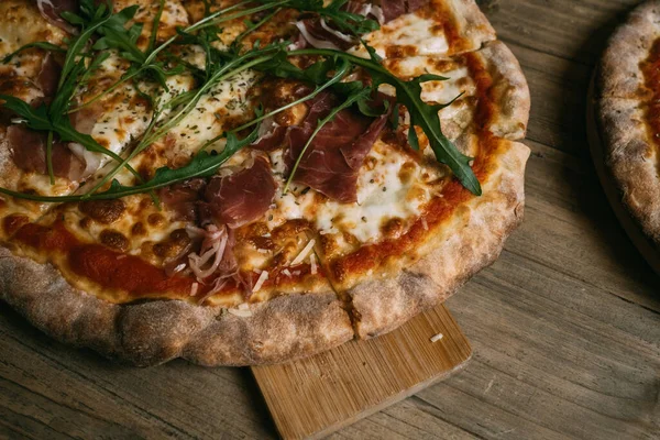 Prosciutto ve ahşap masada salamlı leziz sıcak et pizzası..