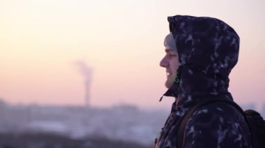 Güzel bir kış gününde şehrin dışında gün batımında bir adamın profili.