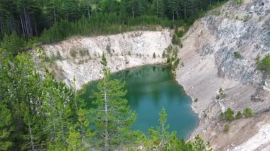 Kozalaklı ağaçlarla çevrili koyu yeşil göl 05