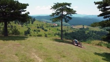 Güneşli bir yaz gününde tepelerin ve dağların güzel manzarasına aşık çiftler için bir bank.