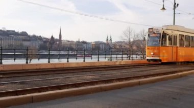 Güneşli güzel bir günde, bir sarı tramvay nehir kıyısından geçer. Orada Avrupa şehrinin manzarasını görebilirsiniz.