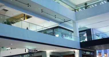 Alışveriş merkezinin zemininde cam çitleri, vitrinleri ve yürüyen insanları olan koridorlar ve geçitler.