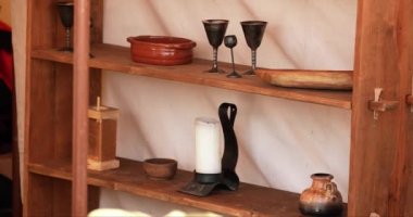 Bir rafa konmuş şamdanın, fincan takımının ve çeşitli ortaçağ eşyalarının iç mekanı.