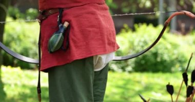 Bir çocuğun ok ve yaydan ateş etmesi için jeton verdiği açık hava etkinliği.