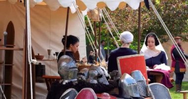 Eski takım elbiseli kızlar, Orta Çağ 'dan kalma zırh ve silahların yanına takım elbise dikiyorlar.