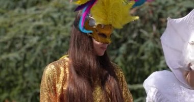 Altın takım elbiseli maskeli animatörler ve tüylü yüz maskesi.