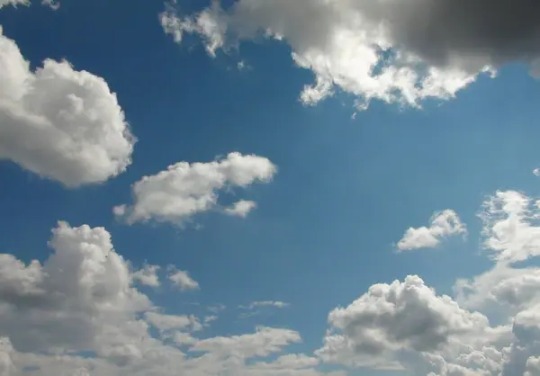 Panorama of the summer morning sky covered with snow-white clouds illuminated by the rays of the sun.