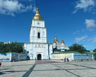 A view from below of the amazing beauty and majesty of the ancient Orthodox cathedral of the historical district of Kyiv against the background of the sunny blue sky.