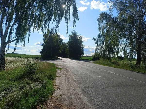A view of a highway intersection in the midday heat reflecting the sun's rays against a blue sky.