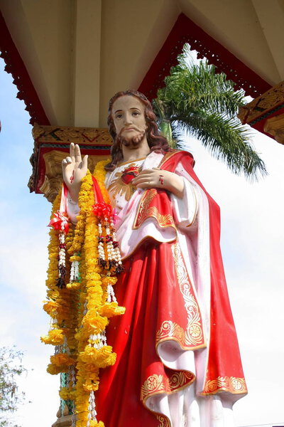Jesus statue is standing in pavilion and Marigold garland hanging on right wrist, Thailand.
