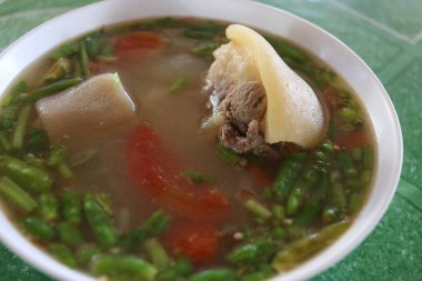 Öküz kuyruğu çorbası beyaz kase, kaynak çorba ve yeşil arka plan, Tayland.