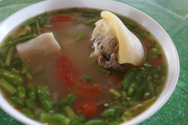 Öküz kuyruğu çorbası beyaz kase, kaynak çorba ve yeşil arka plan, Tayland.