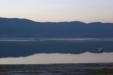 Göl kenarındaki gökyüzünün mükemmel yansıması ve Burdur Gölü, Türkiye 'de günbatımında bir tekne