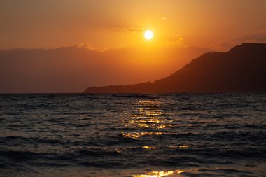 Deniz tarafından gün batımı, gökyüzü denize, günbatımına, yatay fotoğrafa yansıyor.