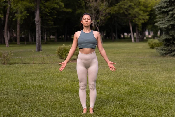 Gün doğumunda halka açık parkta yoga yapan güzel bir kadın.