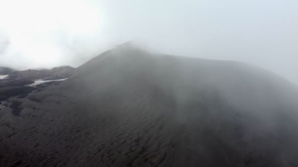 Arrampicata su un vulcano coperto di neve nera tra le nuvole — Video Stock