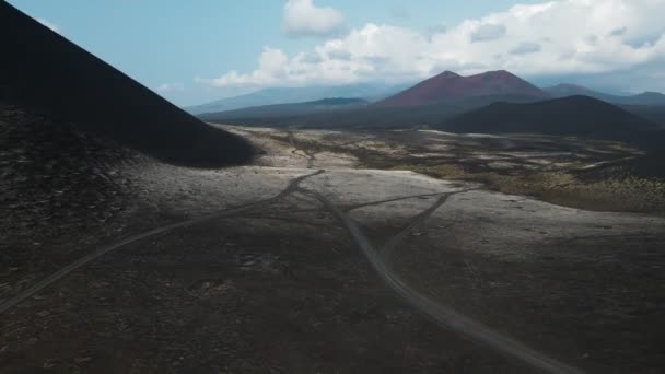 Terre volcanique noire surplombant un volcan rouge — Video