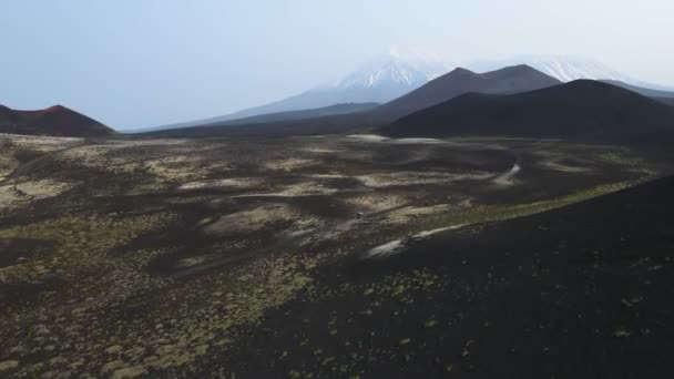 Arabalar volkanlara tepeden bakan kara toprakta yol alırlar. — Stok video