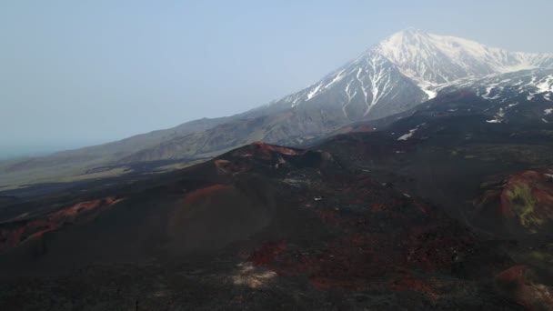 Lave noire gelée surplombant les volcans enneigés — Video