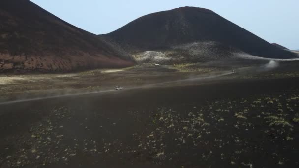 Cars drive on black earth overlooking volcanoes — Vídeo de stock