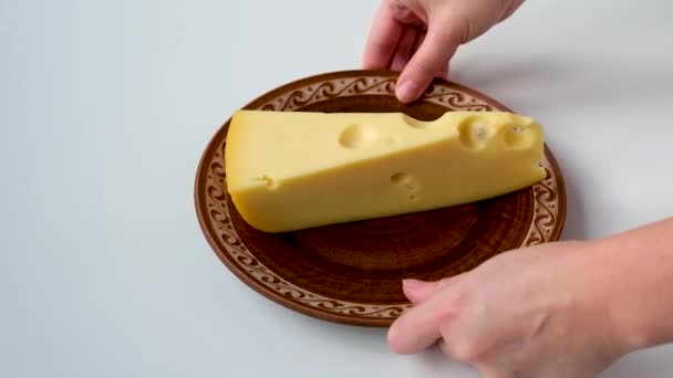 A large piece of cheese lies on a ceramic plate — Vídeo de stock