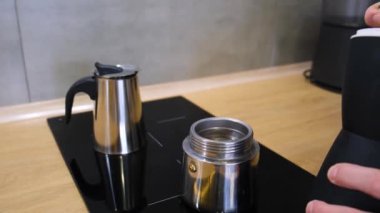 a man at home in the kitchen pours coffee into a geyser coffee maker