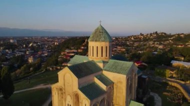 flight over the city of Kutaisi, Georgia. Bagratis Cathedral closeup at sunset.