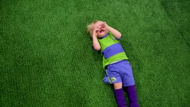 Liten pojke fotbollsspelare ligger på det gröna gräset och gråter — Stockvideo
