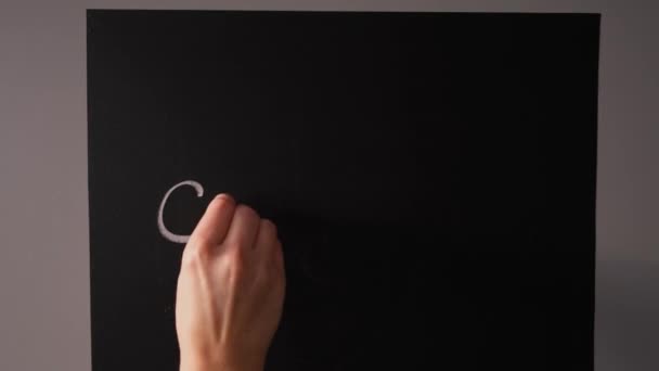 Girl writes on a chalk board with chalk the word sorry — Stock Video