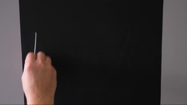 Boy writes on a chalk board with chalk the phrase fuck you – Stock-video