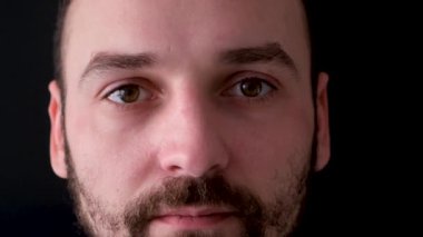 Kahverengi gözlü genç bir adam kendinden emin bir şekilde kameraya bakıyor.