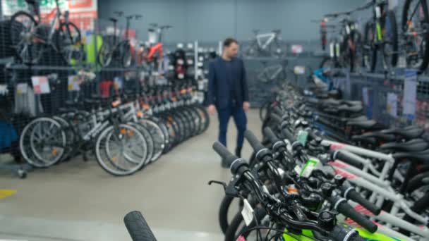 En man i affärskläder väljer en cykel i en sportaffär — Stockvideo