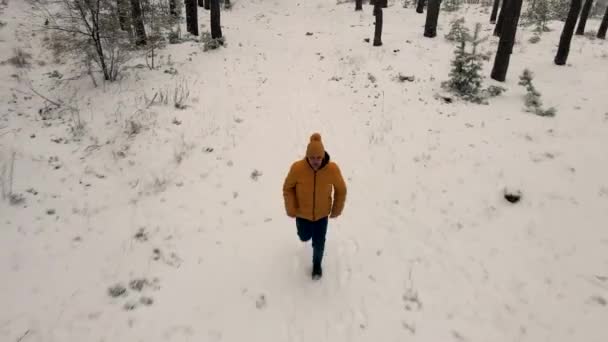 Mężczyzna biegnie samotnie po śnieżnym lesie twarzą do kamery. — Wideo stockowe