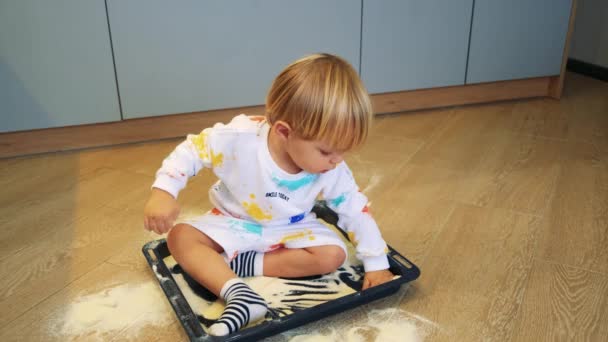 Małe dziecko bawi się mąką w kuchni jak piasek siedzi w naczyniu kuchennym — Wideo stockowe