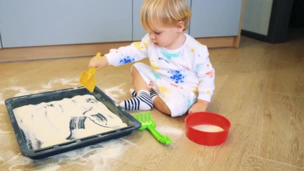 Małe dziecko bawi się mąką w kuchni bierze mąkę łopatą jak w piaskownicy — Wideo stockowe