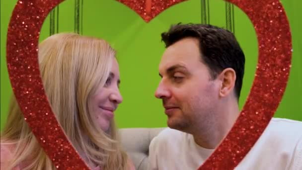 Uma mulher e um homem apaixonado olham um para o outro e seguram um coração decorativo na mão — Vídeo de Stock