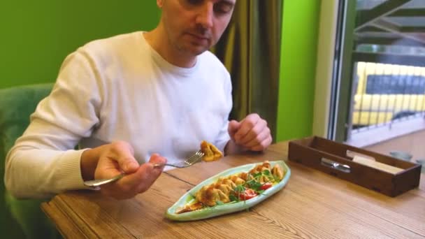 Kafkasyalı bir adam restoranda kızarmış Vietnam mantısı yiyor. — Stok video