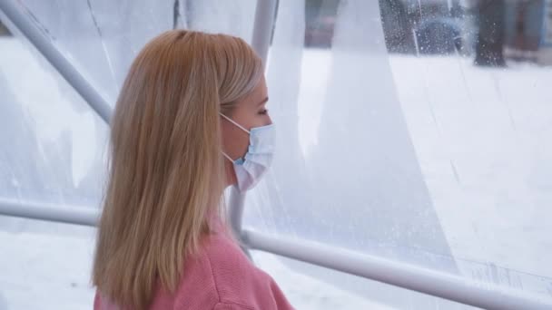 A woman in a mask leaves a fingerprint on a misted window — Stock Video