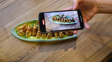 Kız blogcu, akıllı telefonunda yemek olan bir yemeği vuruyor.