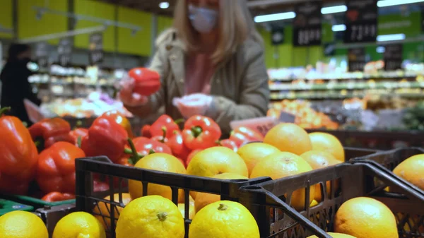 Dziewczyna w dziale owoców w supermarkecie wybiera czerwony papryka — Zdjęcie stockowe