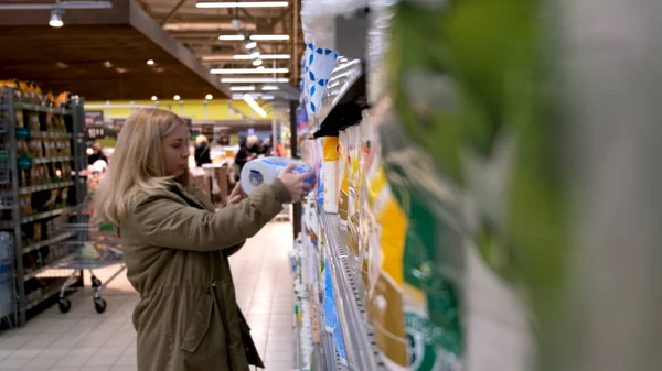 Blonde femme ramasse des marchandises dans le département d'entretien ménager d'un supermarché — Photo