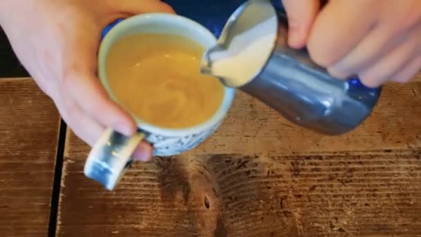 Barista fa il cappuccino in una tazza di ceramica versa il latte nel caffè — Video Stock