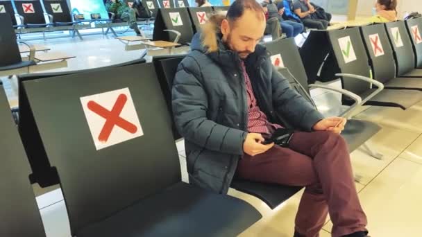 A man at the airport sits in the waiting room enters information from the credit card into the phone — Stock Video