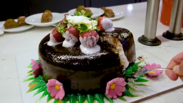 Pánská ruka vytáhne kousek krájeného čokoládového koláče s jahodami — Stock video