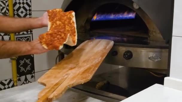 The cook lays the pizza on a wooden shovel and sends it to a burning oven — Video