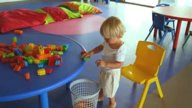 Küçük bir çocuk inşaat setiyle oynar ve ellerini çırpar.