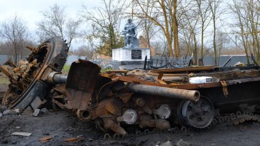 Ukrayna 'daki bir askerin anıtının arka planında kaza yapmış bir askeri araç. Irpin-Kyiv - Nisan 2022